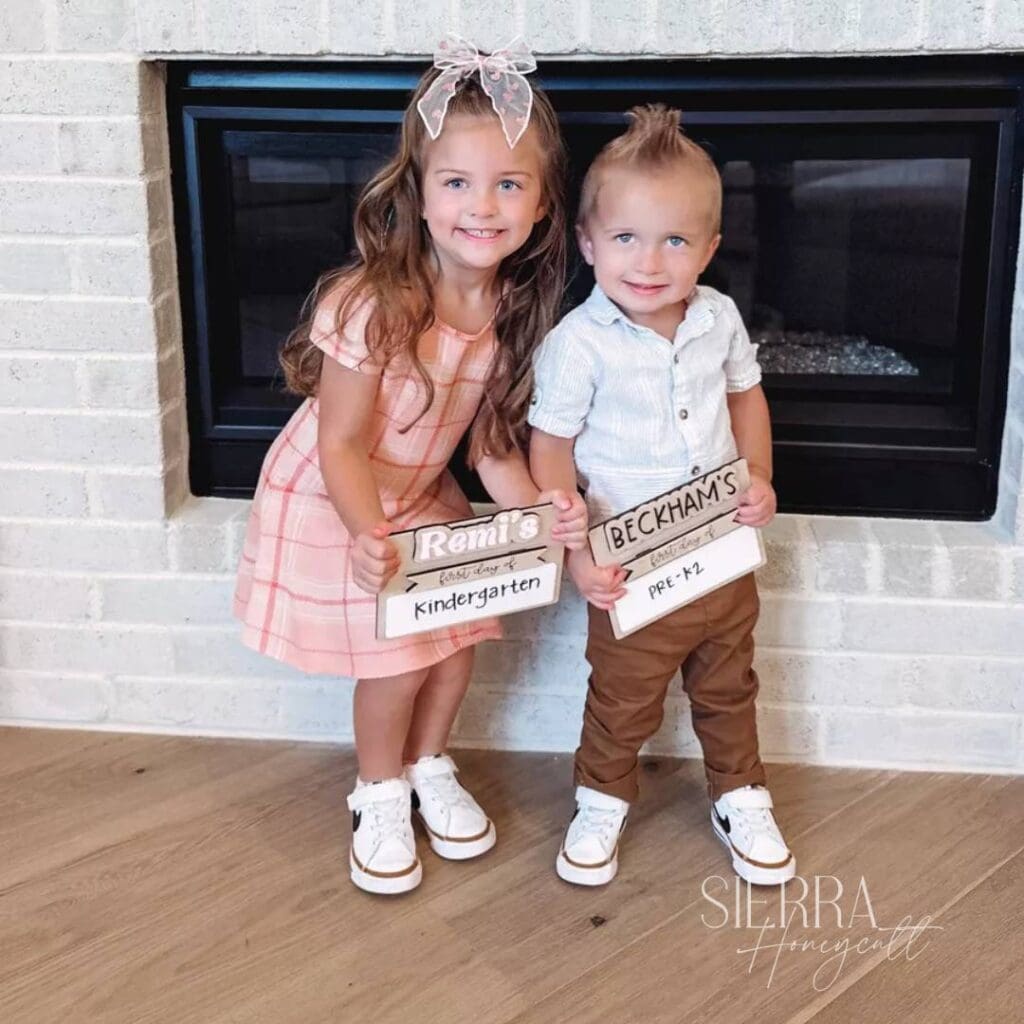 Sierra Honeycutt's kids holding back to school signs, smiling.